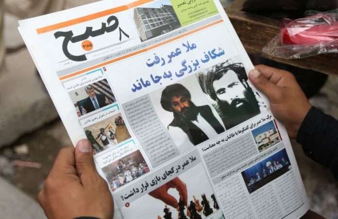 Afghan man reads a local newspaper abut the death of Omar